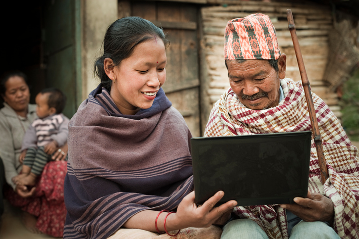 Young person teaching grandfather how to use new technology thanks to new connectivity in their remote area