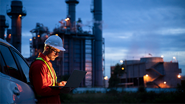 man on laptop outside energy plant