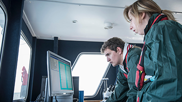 people on ship looking at computer