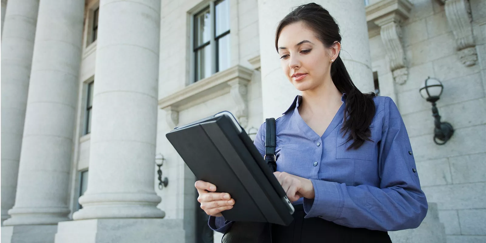 woman outside federal building on tablet